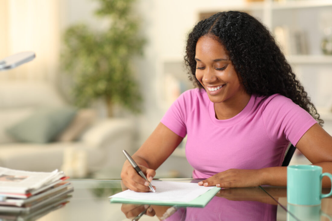 Happy black woman filling form at home